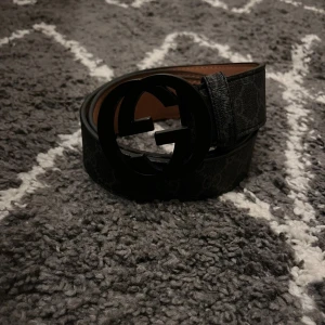 G-bälte - En snygg bälte som är i svart g monogram och har en svart G-spänne där framme i bältet. Strl 110cm 