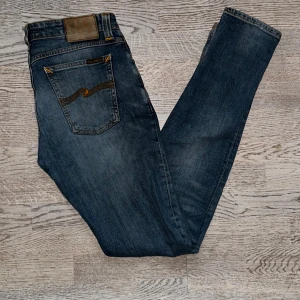 Nudie jeans - Säljer ett par blåa skinny jeans från Nudie med klassisk femficksdesign och snygg slitning på vänster knä som man ser På bild 2️⃣. Storleken är W29 L34 på etiketten men jag sitter mer som W30. Skick: 9/10 Modell: Slim