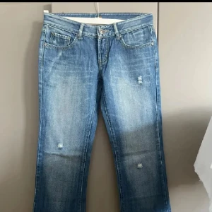 Blå jeans från 7 For All Mankind - Snygga blå jeans från 7 For All Mankind med klassisk femficksmodell och gul brodyr på bakfickorna. Jeansen har lätt slitna detaljer framtill och raka ben. Tillverkade i mjuk bomullsdenim med autentisk tvätt och kontrastsömmar.