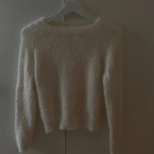 Vit fluffig tröja från SHEIN - Supermjuk och fluffig vit tröja från SHEIN i storlek S. Tröjan har lång ärm och är gjord i polyester vilket gör den riktigt skön och varm. Perfekt för dig som gillar en enkel men cozy look med lite extra fluff.