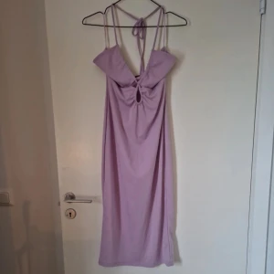 Ljuslila cut-out klänning - Lila klänning som knyts bakom halsen och cut outs vid bysten. Storlek M och köpt second hand men den är endast provad och i fint skick. Katt finns i hemmet