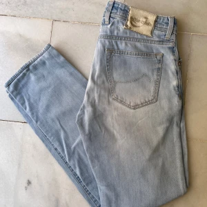 Ljusblå jeans från Jacob Cohen, strl 34 - Snygga ljusblå jeans från Jacob Cohen i klassisk rak modell. Jeansen har en cool patch i mocka med broderad logga bak och detaljerade sömmar. Tillverkade i mjukt bomullsmaterial för skön passform. Perfekt för dig som gillar stilrena och exklusiva jeans.