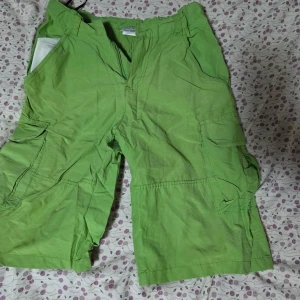 Gröna cargo shorts från Knot So Bad - Säljer ett par gröna cargo shorts från Knot So Bad med flera praktiska fickor på sidorna och klassisk dragkedja framtill. Modellen är loose fit och har midwaist. Perfekta för chill dagar och häng med kompisarna. Materialet är mjuk bomull.