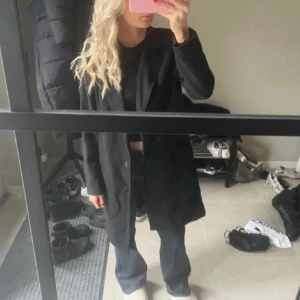 Svart medellång kappa  - Svart medellång kappa från amy’s stories, använd fåtal gånger! Storlek 38 men skulle säga att den är mer en S