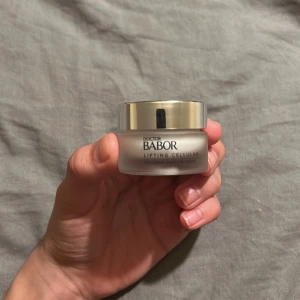 Babor Lifting Cellular Collagen Booster Cream - Säljer en Babor Lifting Cellular Collagen Booster Cream i en snygg frostad glasburk med silvrigt lock. Krämen är vit och har en lyxig konsistens, perfekt för dig som vill boosta huden med kollagen. Burken rymmer 15 ml och är tillverkad i Tyskland.