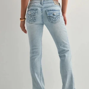 Ljusblå bootcut jeans från True Religion - Säljer ett par ljusblå jeans från True Religion helt oanvända. Jeansen har snygga broderade bakfickor med lock och silverfärgade knappar. Perfekt för dig som gillar detaljer och ikonisk stil. Kom privat för mer bilder. Köpte för 1299kr. Långa ben