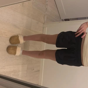 Svarta träningsshorts från Lululemon - Säljer ett par svarta träningsshorts från Lululemon med elastisk midja och diskret logga på sidan. Shortsen har en loose passform och är gjorda i ett lätt syntetmaterial som andas, perfekta för gymmet eller löprundan.