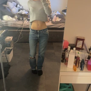 Blå raka jeans från zara - Säljer ett par klassiska blå jeans från Zara med rak passform och mid/låg midja. Jeansen har slitning ena vid knät och coola detaljer som fem fickor. Perfekt för dig som gillar en avslappnad och tidlös look.