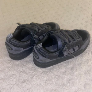 Adidas grå sneakers ADI2000 - Säljer ett par Adidas sneakers i mörkgrå och svart färg med klassiska ränder på sidan. Perfekt för dig som gillar chunky streetstil! Pris kan diskuteras💞