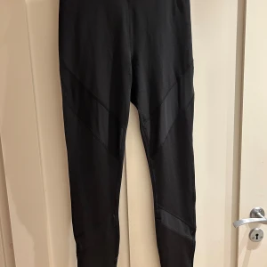 Svarta leggings från Even&Odd Active - Svarta leggings från Even&Odd Active i storlek S. De har en hög midja och är tillverkade i ett stretchigt syntetmaterial som passar perfekt för träning. Snygga paneldetaljer längs benen ger en sportig vibe. Supersköna och flexibla för alla dina aktiva dagar.