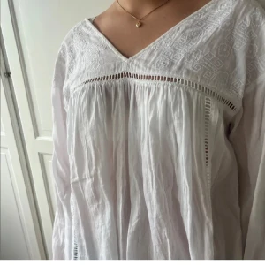 Vit blus med beoderier  - Vit blus med broderier, öppen i ryggen, V ringning och blommor