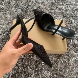 Svarta spetsiga pumps med broderi - Säljer ett par svarta pumps med spetsig tå och smal klack. Skorna har en tunn rem över foten och är dekorerade med broderade detaljer och pärlor framtill. Materialet ser ut att vara syntet med glansig finish. Perfekta för dig som gillar en elegant och edgy look.