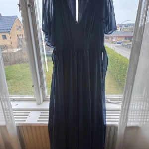 Mörkblå långklänning från Bubbleroom - Säljer en elegant mörkblå långklänning från Bubbleroom med v-ringning och transparenta korta ärmar. Klänningen har ett flowy fall och är tillverkad i ett lätt, skönt polyestertyg. Perfekt för dig som vill ha en stilren och klassisk look. Normal i storleken, endast använd en gång. Färgen ser ut som på den sista bilden. 