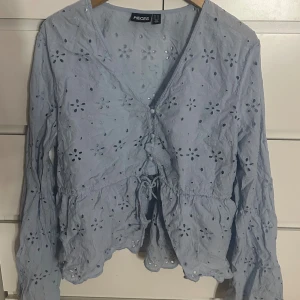 Ljusblå blus med broderade blommor från Pieces - Superfin ljusblå blus från Pieces med broderade blommor och hålmönster. Blusen har v-ringning. Perfekt för vår och sommar! Liten i storlek och något kort. Ska såklart strykas!! Nypris 449kr
