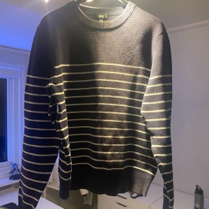 Randig mörkblå tröja från Uniqlo - Säljer en snygg mörkblå tröja från Uniqlo i storlek S. Tröjan har vita horisontella ränder över hela kroppen och ärmarna, rund hals och ribbade muddar. Materialet är mjukt och stickat, perfekt för dig som gillar enkel och stilren design.