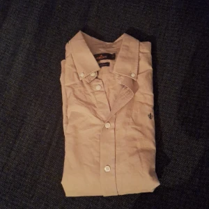 Morris Skjorta - Snygg beige skjorta från Morris Stockholm i storlek M. Tillverkad i bomull med Twofold Yarn för extra kvalitet. Klassisk krage, långa ärmar och knappar framtill. Diskret Morris-logga broderad på bröstet. Perfekt för dig som gillar stilrena och tidlösa plagg. Oanvänd, säljer på grund av att den inte kom till användning🙌🏼