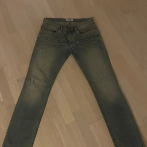 Grå Acne Max Draw jeans 32/32 - Säljer ett par gråa Acne Max Draw jeans i storlek 32/32. Dom har en snygg tvättad look med subtila slitningar. Ny pris 4500, riktigt bra skick