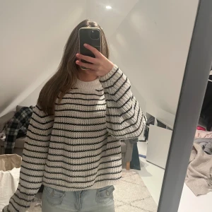 Randig stickad tröja Gina Tricot XS - Säljer en vit och svart randig stickad tröja från Gina Tricot i storlek XS. Tröjan har en rund halsringning, långärmade ärmar och en loose passform. Perfekt för dig som gillar en chill och trendig look med breda ränder och grovstickat material.