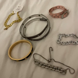 Mix av coola armband i olika färger - Säljer ett gäng snygga armband: ett chunky guldarmband, ett silverfärgat kedjearmband, ett rosa läderarmband med nitar, två smala gråa wrap-armband med glittriga detaljer, ett svart och guldigt bangle med små nitar samt ett silverfärgat armband med strass. Perfekt för dig som gillar att mixa stilar!