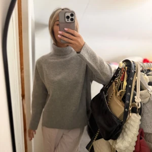 Grå polotröja i mjuk stickad ull - Säljer en grå polotröja med hög krage i mjuk stickad ull. Tröjan har lång ärm och en loose passform som ger en chill vibe. Perfekt för kalla dagar när du vill vara både bekväm och snygg. Enkel design utan detaljer, passar till allt. Storlek L men skulle säga mer som S. Aldrig använd 