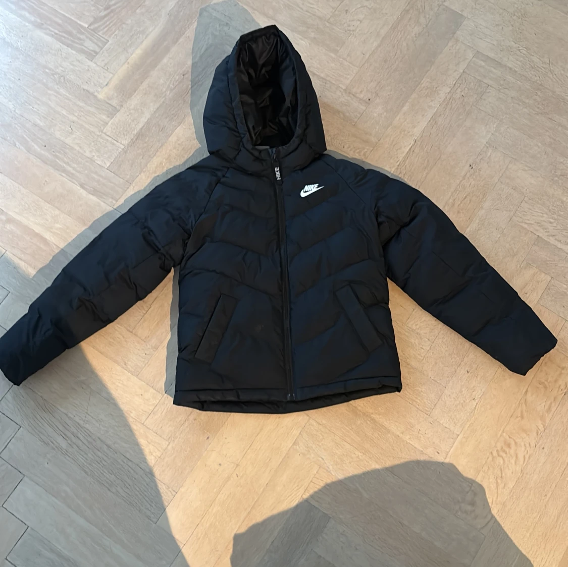 Svart pufferjacka från Nike med huva