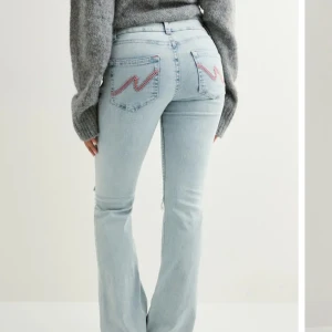 Ljusblå bootcut jeans från Nelly - Säljer ett par ljusblå jeans från Nelly som är bootcut med hål på knäna och fina rosa detaljer. Säljer för de inte kommer till andvändning.