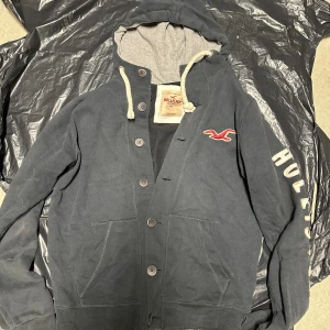 Vintage Hollister hoodie med knappar - Extremt eftertraktad och sällsynt vintage  Hollister hoodie med knappar! Grymt skick, inga defekter - ser exakt ut som på bild! Ingen Storleks lapp, troligen M. Skriv vid frågor!💬