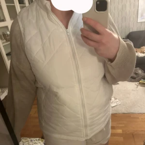 Vit dunväst med dragkedja - En vit dunväst med quiltat mönster och hög krage. Västen har hel dragkedja framtill och två fickor med dragkedja. Lite tunn så du vet innan så passar mer om man har en hoodie under nu på hösten på våren är den perfekt. Den är XL men väldigt liten i storleken så skulle säga M (jag på bilden brukar ha S/M) . Säljer åt min mormor så vet inte vart den är ifrån (de visste inte hon heller ) men hon hade precis köpt den o den va för liten för henne