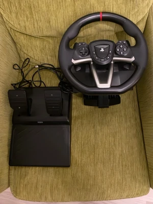 Gaming ratt till ps4 ps5 och pc - Säljer en svart racingratt och pedalset från Hori till Playstation. Ratten har flera knappar, PlayStation-logga i mitten och en sportig design med silverdetaljer. Pedalerna är i plast och ansluts med kabel. Perfekt för racing- och bilspel. Använd ca 12 gånger 