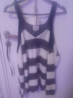 Randigt stickat linne från Vero Moda - Säljer enstickat tröja från Vero Moda Denim med öppna axlar, breda svarta och vita ränder. 