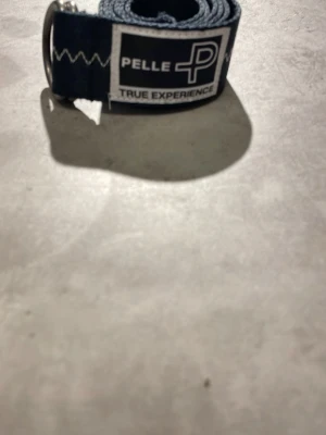 Mörkblått tygbälte från Pelle P - Snyggt mörkblått tygbälte från Pelle P med vitt märke och texten 'True Experience'. Bältet har silverfärgat D-ring spänne och dekorativa vita sömmar längs hela bandet. Perfekt accessoar för att lyfta din outfit.