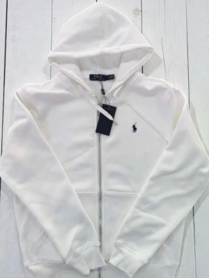 Polo Ralph lauren hoodie  - Vit Polo Ralph Lauren Hoodie  Stilren vit hoodie i klassisk design ✨ Mjukt och bekvämt material som passar perfekt till vardag 👌 Plagget är aldrig använt och i nyskick 🧥 Enkel att matcha för en clean outfit 💎  🔹 Märke: Polo Ralph Lauren 🔹 Färg: Vit 🔹 Skick: Aldrig använt 🔹 Passform: Klassisk 📦 Snabb leverans 