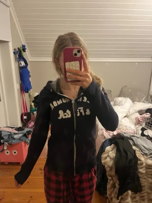 Marinblå hoodie Abercrombie & Fitch - Säljer en marinblå hoodie från Abercrombie & Fitch med dragkedja och vit broderad logga på bröstet. Hoodien har huva med grått innerfoder och två fickor framtill. Perfekt för chill dagar och enkel att matcha med jeans eller mjukis. Liten i storleken 