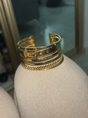 Michael Kors armband - Guldigt armband från Michael Kors med flera lager. Kommer inte till användning hos mig. Köptes för ca 1600kr