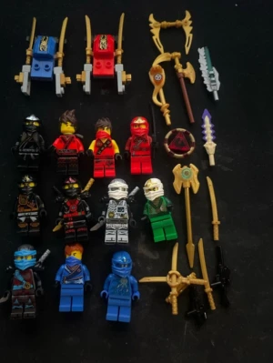 Lego Ninjago figurer och vapen - Samling med Lego Ninjago minifigurer i olika färger som svart, röd, vit, grön och blå. Medföljer flera tillbehör som svärd, spjut, sköldar och två små fordon i blått och rött. Perfekt för dig som gillar Ninjago och vill bygga egna äventyr.