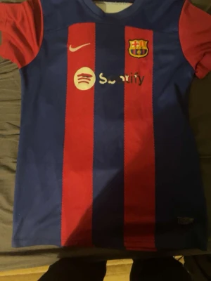 Barcelona matchtröja Nike blå/röd - Säljer en FC Barcelona matchtröja från Nike i klassiska blå och röda vertikala ränder. Tröjan har klubbmärke, Nike-logga och Spotify som sponsor på bröstet. Tillverkad i lätt och ventilerande material, perfekt för fotboll eller träning.
