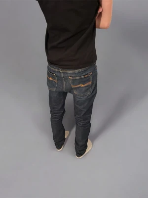 Mörkblå slim fit jeans från Nudie - mörkblå jeans från Nudie med klassiska raka ben och kontrastsömmar på bakfickorna. Tillverkade i slitstarkt jeansmaterial av bomull. Jeansen är i storlek W33 L34. Skriv om du vill veta något mer.