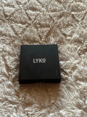 Lyko Compact Powder Pressat Puder - Säljer ett Lyko Compact Powder pressat puder i färg 01. Kommer i en stilren, svart fyrkantig dosa av plast med Lyko-loggan på locket. Innehåller 10g puder och är tillverkat i Italien. Perfekt för att matta ner huden och fixa basen.