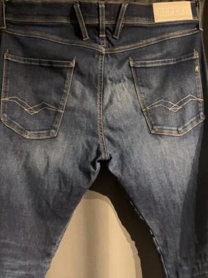 Replay Anbass Jeans Blå - Trendiga Replay-jeans i blå denim med snygg tvätt och stilrena detaljer. Klassisk Replay-design med broderade bakfickor och logopatch i midjan. Bekväm passform och enkla att matcha till både vardag och fest.   Tar gärna emot bud 💸 Skriv vid frågor eller funderingar 📩✨