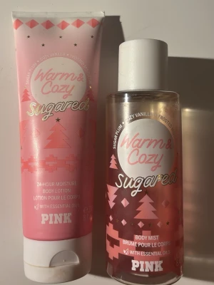 Warm & Cozy Sugared Body Mist & Lotion - Set med body mist och body lotion från Victorias Secret  PINK i doften Warm & Cozy Sugared. Flaskorna är rosa med vita och guldiga detaljer, dekorerade med grafiska mönster och text. Innehåller eteriska oljor och har en söt, vaniljig doft med inslag av sockerplommon.
