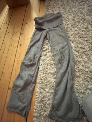 Grå mjuka loungewear-byxor Gina Tricot - Supermysiga grå loungewear-byxor från Gina Tricot med bred ribbad midja och utsvängda ben. Perfekta för chill hemma eller när du vill vara extra bekväm. Tillverkade i mjukt stickat material som känns skönt mot huden. Dem ät lite noppriga men funkar toppen!