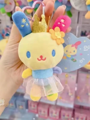 Regnbågsfärgad kanin nyckelring - Söt nyckelring i form av en kanin med regnbågsfärgade detaljer, blått och rosa öra, gul kropp och blå tröja. Ena varianten har en guldfärgad krona och tyllkjol, den andra har rosa rosetter på öronen. Perfekt att hänga på väskan eller nycklarna.