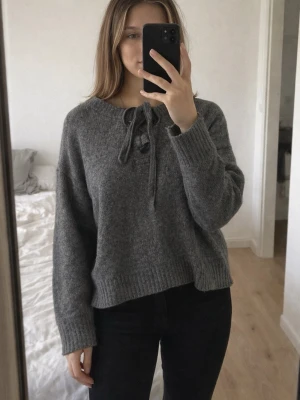 Grå stickad tröja med knytning - Mysig grå stickad tröja med knytning vid halsen från Zara. Tröjan har inte används så mycket. Storleken är M men passar även en lite större S. 
