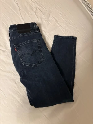  Levi's jeans - Snygga mörkblå jeans från Levi's med klassisk femficksdesign och rakt bensnitt. Jeansen har den ikoniska röda Levi's-lappen på bakfickan och svart läderpatch i midjan. Perfekta för en avslappnad och stilren look. Storlek w29 l30 dessa är i toppskick! Knappt använda och köpta nya i butik!