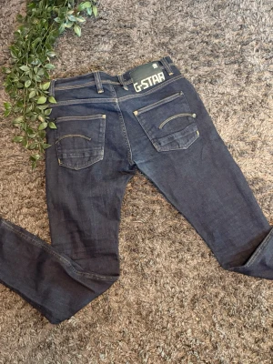 Mörkblå jeans från G-Star  - Säljer ett par mörkblå jeans från G-Star RAW med raka ben och snygga detaljer på bakfickorna. 
