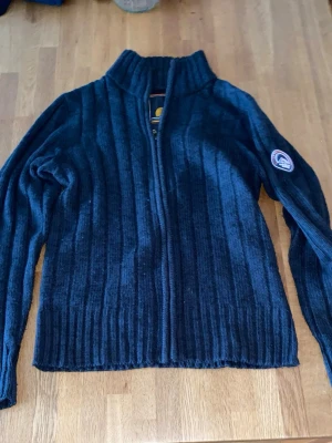 Mörkblå stickad ziptröja - Mörkblå stickad ziptröja  med ribbad struktur och hög krage. Tröjan har dragkedja framtill. Perfekt för lager-på-lager och snygg till jeans.