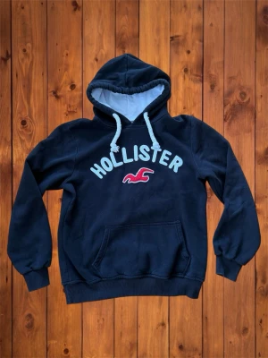 Vintage Hollister hoodie (sällsynt) - Säljer denna vintage, sällsynta och asfeta hoodien från Hollister. Den är riktigt fet och har snygg design på framsidan. Storlek är M men skulle säga att den passar som en S se måtten nedan B=64cm A=55cm