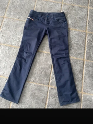 Mörkblå bootcut jeans - Mörkblå bootcut jeans som är väldigt lågmidjade. Midjemåttet tvärs över är 42 cm. Klassisk 5-ficksdesign med knapp och dragkedja. Passar lika bra till vardags som till mer uppklädda tillfällen. Jeansen är i gott skick, välvårdade och redo för ny ägare. 