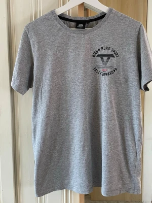 Grå Björn Borg Sport t-shirt - Snygg grå t-shirt från Björn Borg Sport med tryck på bröstet. Klassisk rund halsringning och korta ärmar. Tillverkad i mjuk bomull som känns skön mot huden. Perfekt för en sportig och avslappnad stil.