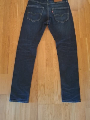 Levi's 511 mörkblå slim fit jeans 28/32 - Säljer ett par Levi's 511 jeans i mörkblå tvätt med klassiska kontrastsömmar och femficksmodell. Jeansen har slim fit passform och är tillverkade i slitstarkt jeanstyg. Perfekta för dig som gillar en smal siluett och tidlös look.
